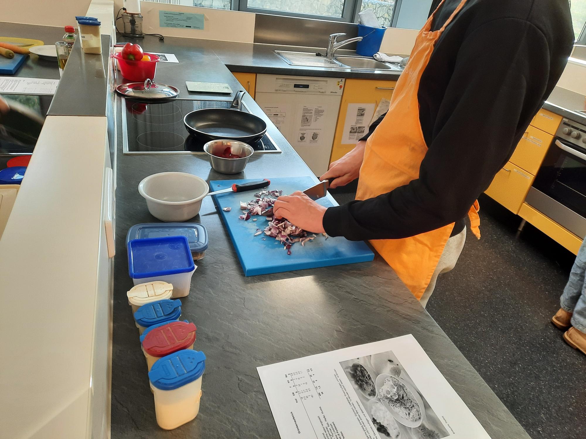 Person schneidet Fleisch auf einem Schneidebrett in einer Küche.