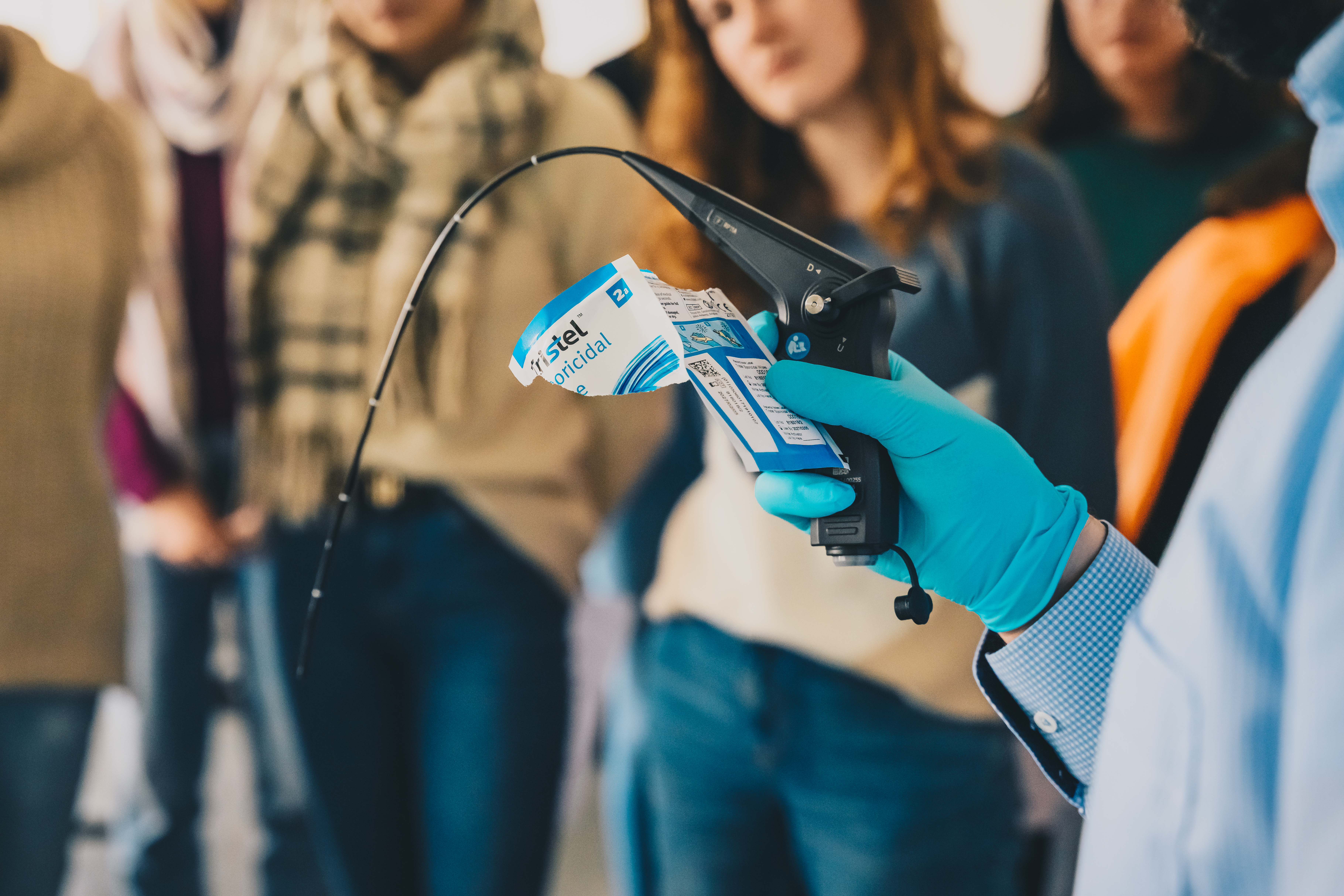 Person hält ein medizinisches Gerät, umgeben von Menschen.