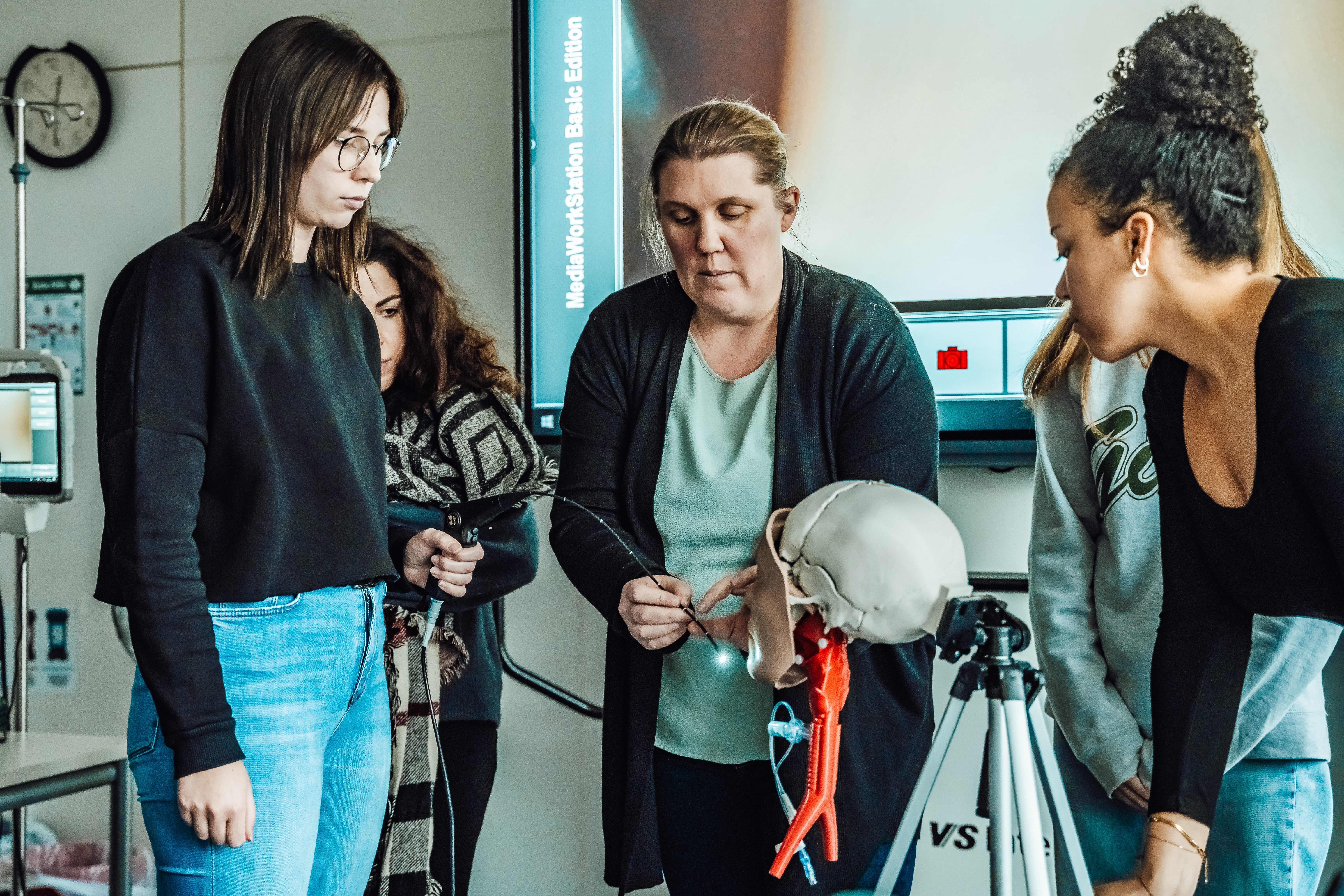 Vier Personen untersuchen einen Schädel, der auf einem Stativ montiert ist.