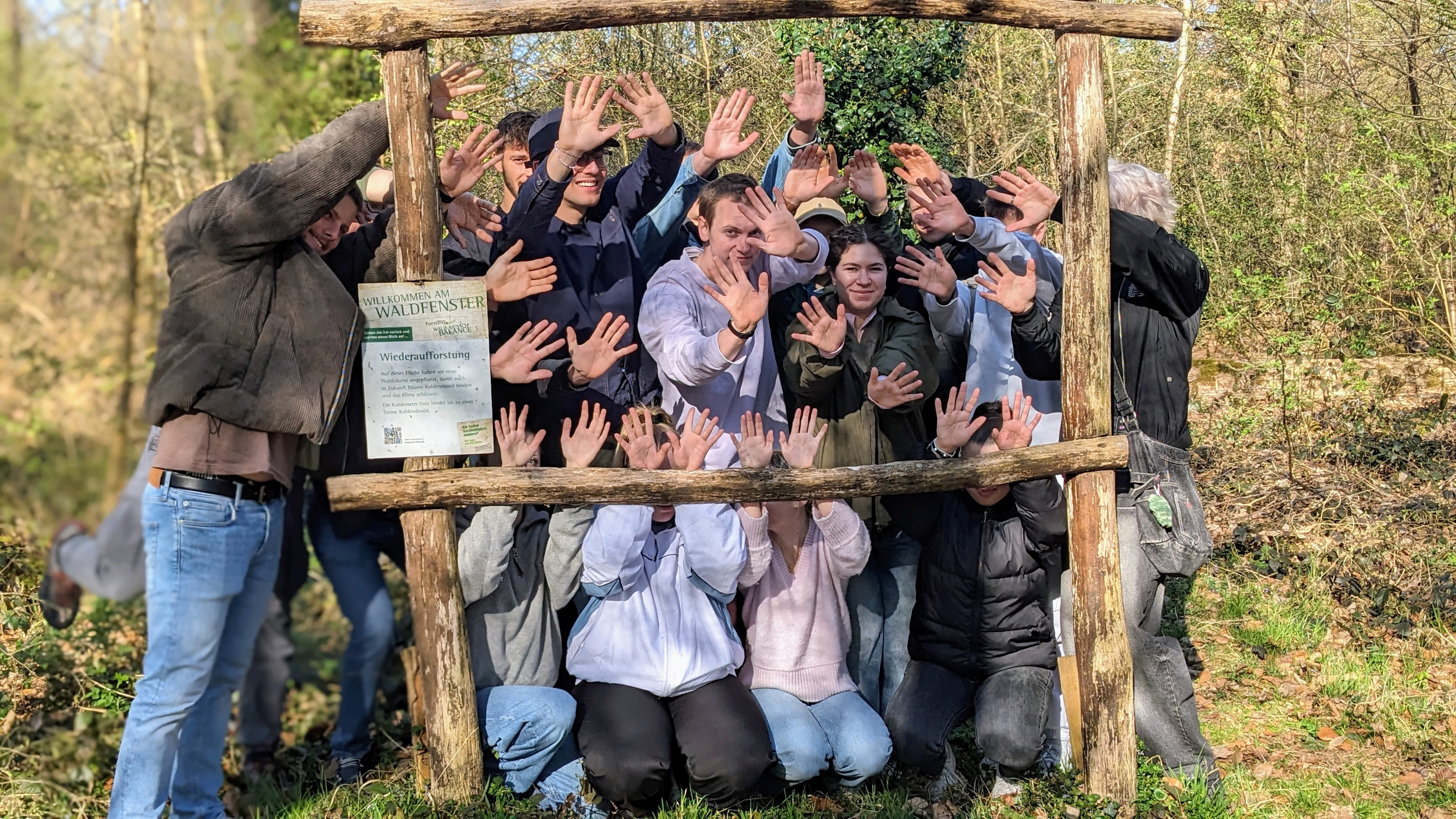 Eine Gruppe von Menschen feiert um ein hölzernes Ziel, die Arme hoch.