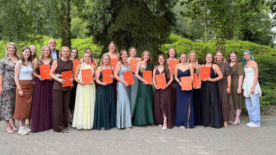 Abschlusskurs steht für ein Gruppenbild lächelnd zusammen