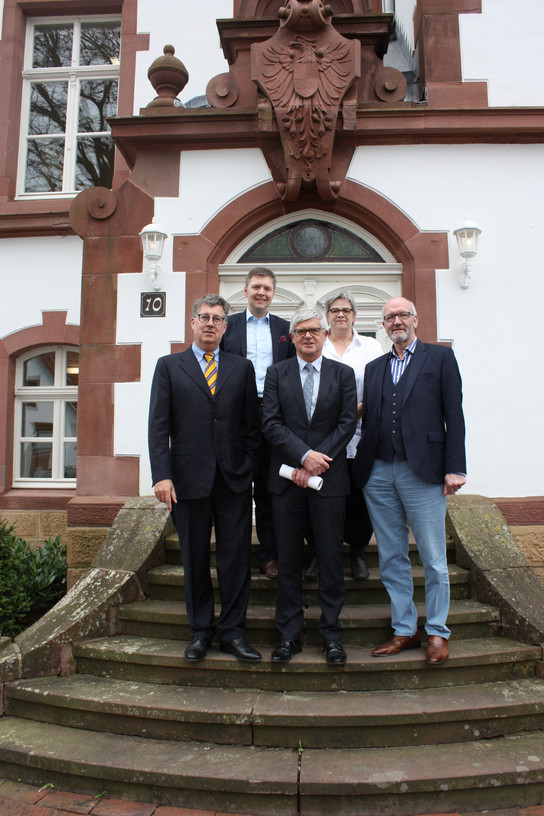 Fünf Männer posieren vor einem Gebäude mit Treppe.