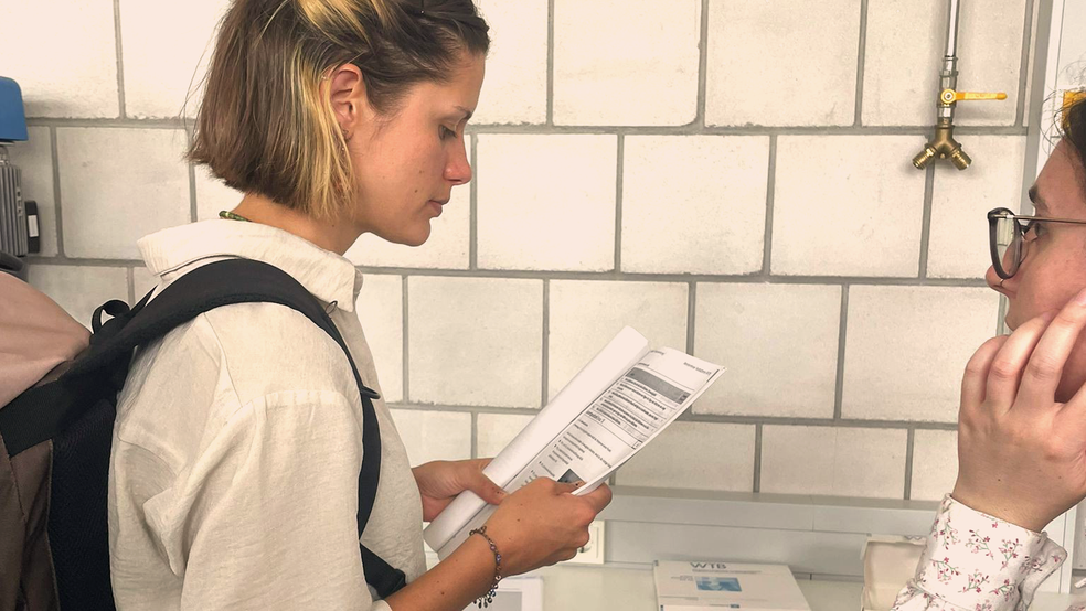 Eine Frau zeigt einem Mädchen ein Dokument an einem Tisch.