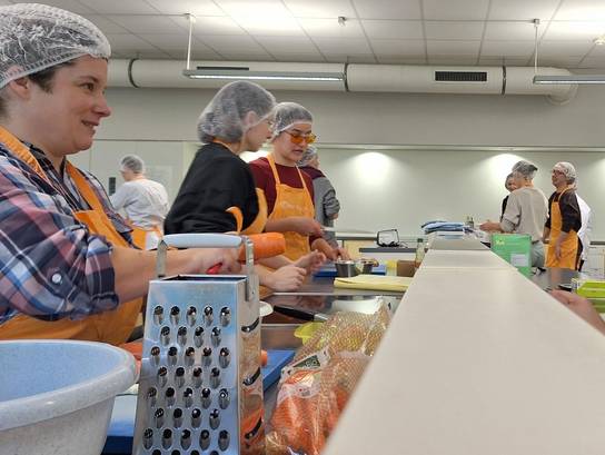 Eine Gruppe von Menschen bereitet Lebensmittel in einer Küche vor.