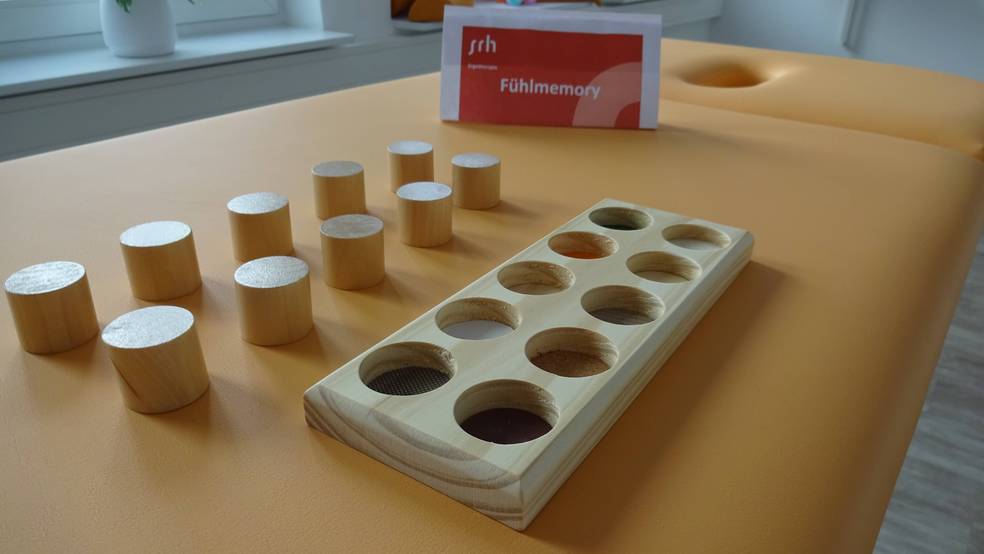 Holzspielzeug auf einem gelben Tisch, einschließlich Zylindern und einem Lochbrett.