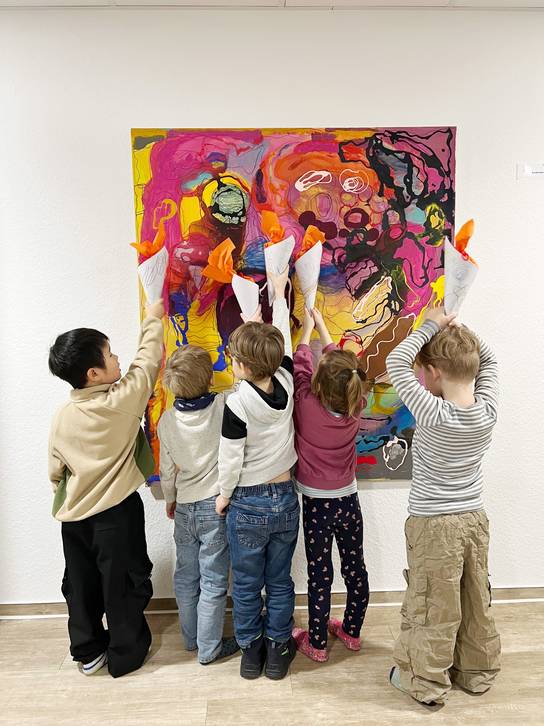 Eine Gruppe von Kindern steht vor einem großen, farbenfrohen Gemälde und betrachtet es.