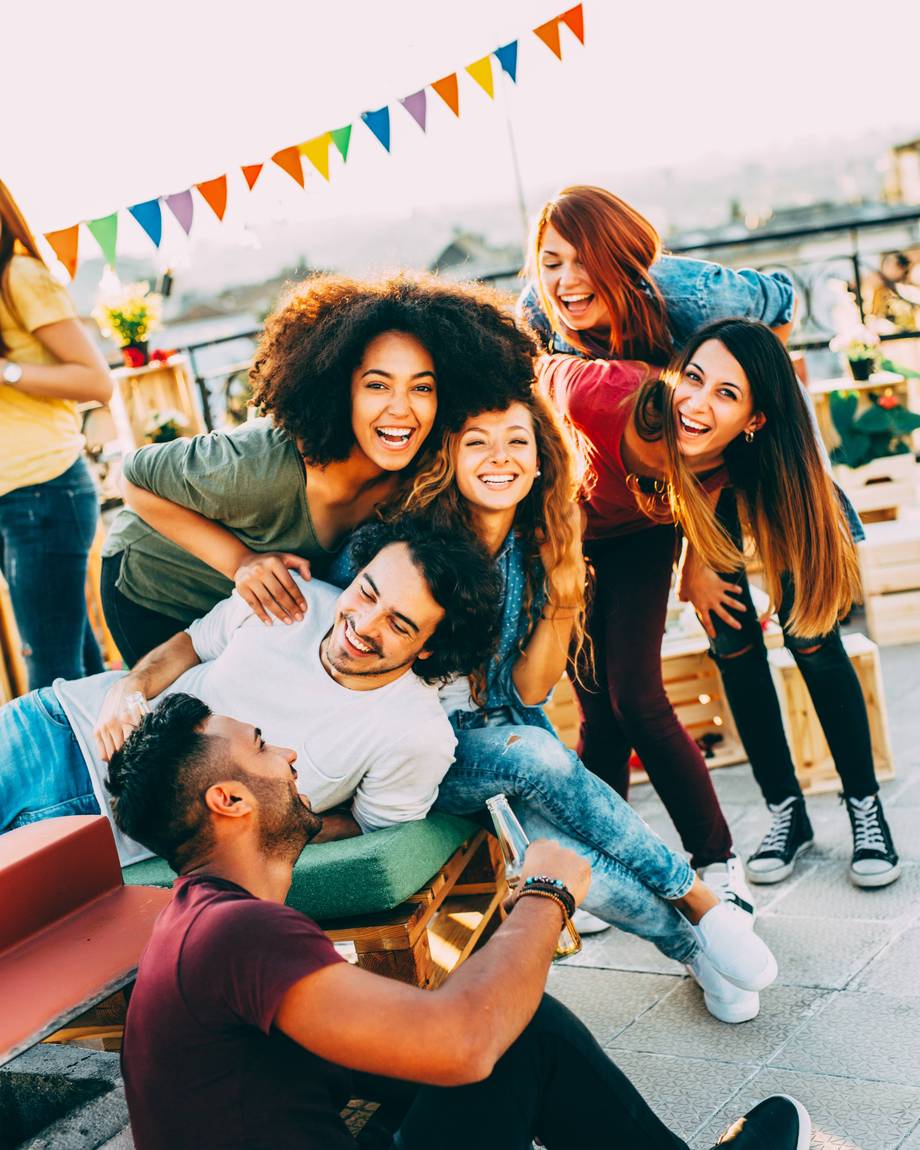 Eine Gruppe von Freunden posiert fröhlich für ein Selfie auf einer Terrasse.