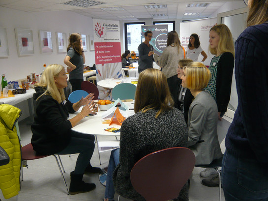 Eine Gruppe von Menschen sitzt und steht in einem Raum und nimmt an einer Diskussion teil.