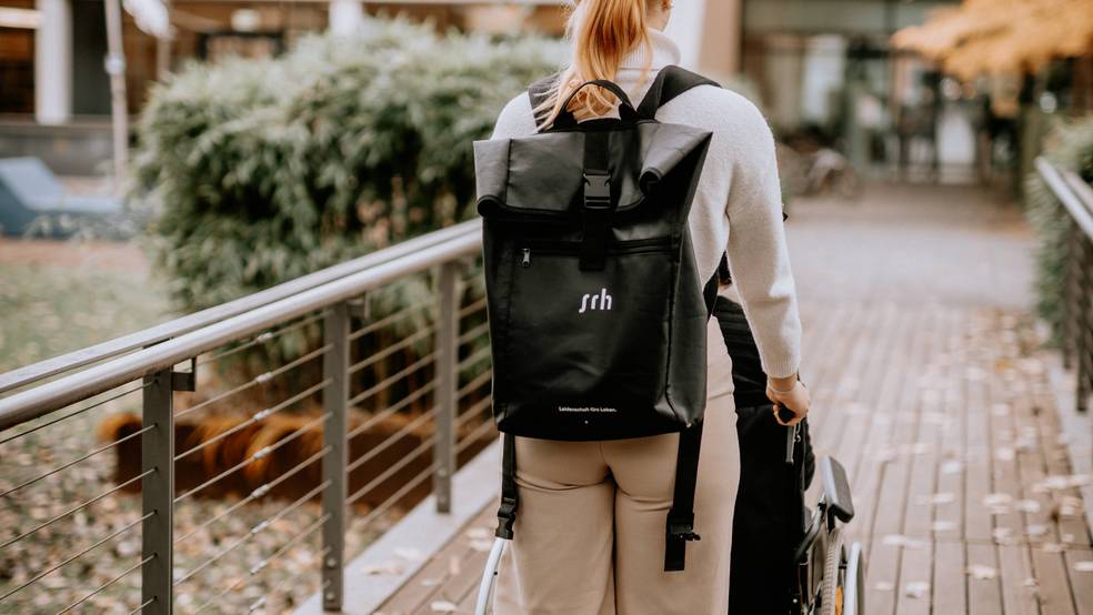 Eine Person mit einem Rucksack geht auf einem Holzweg.