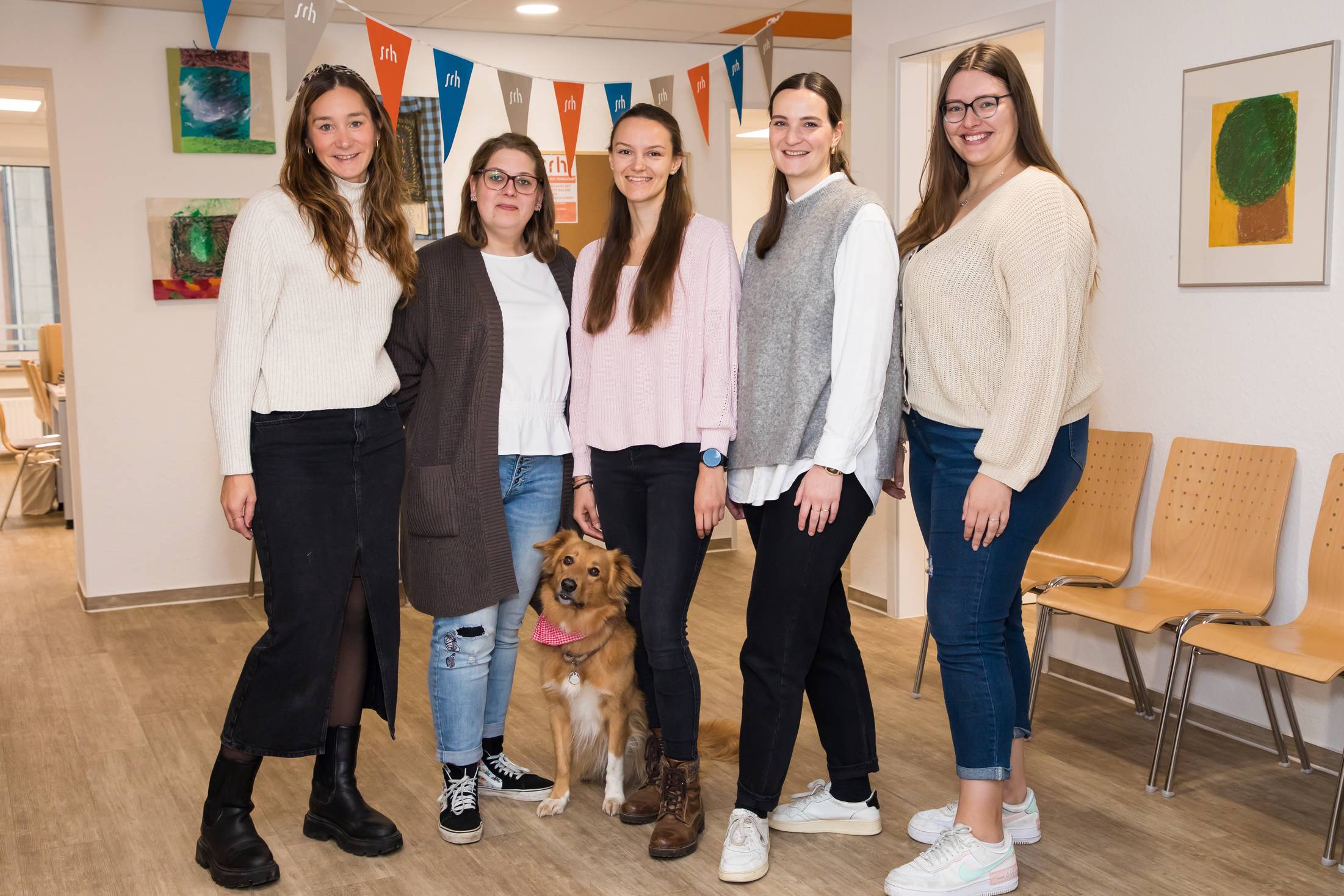 Fünf Frauen und ein Hund posieren in einem Raum.