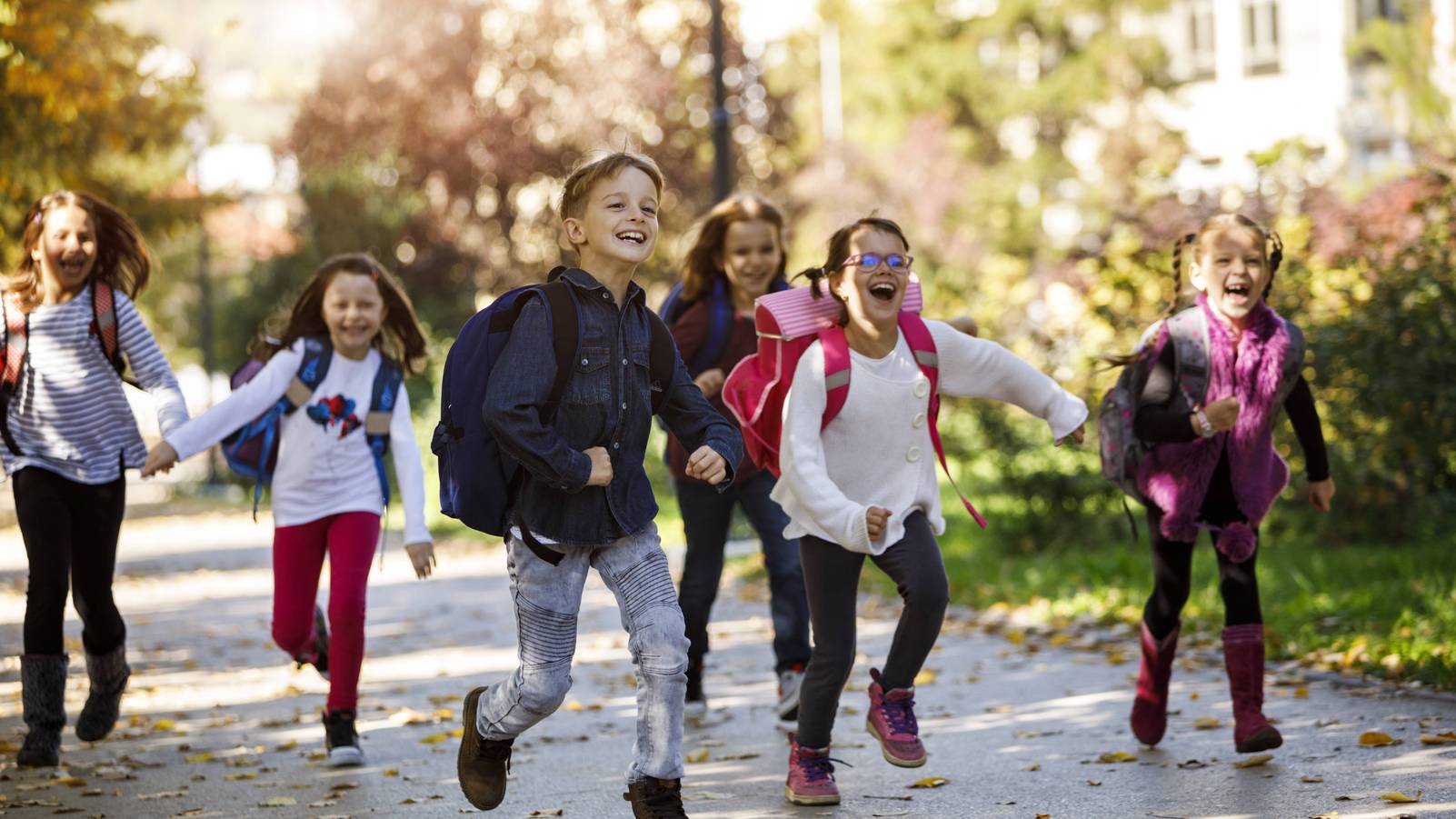 Eine Gruppe von Kindern läuft lachend und spielend in einem Park.