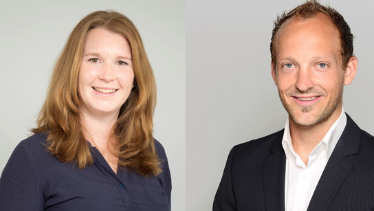 Zwei Personen, eine Frau und ein Mann, lächeln in die Kamera.