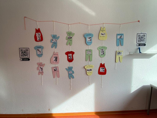 Mehrere bunte Handschuh-Dekorationen hängen an einer weißen Wand.