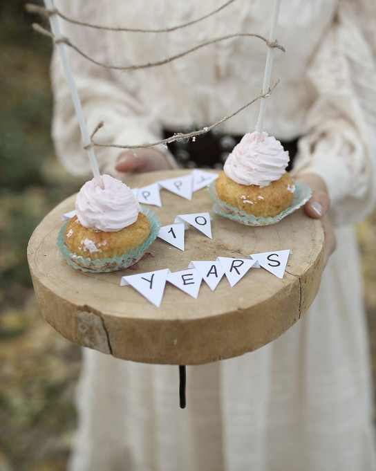 Zwei Cupcakes auf einem Holzteller mit einer "10 Jahre"-Banner.