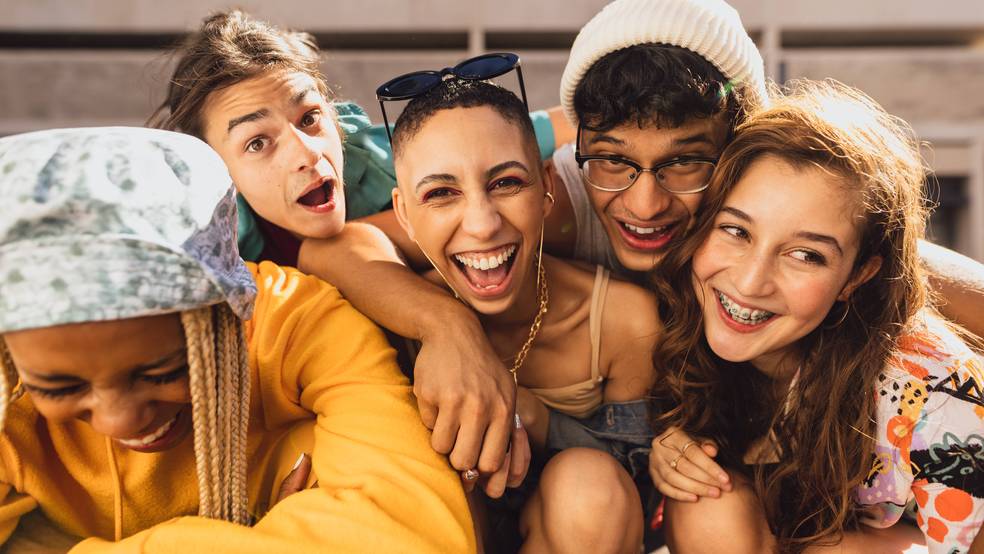 Fünf Freunde posieren lachend und umarmen sich.