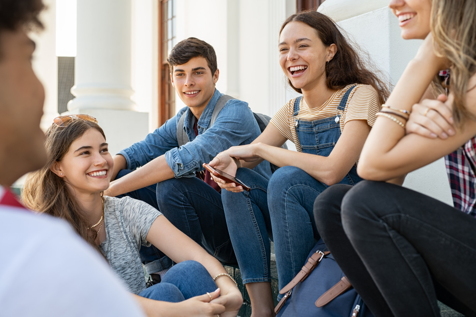 5 lachende Jugendliche sitzen zusammen