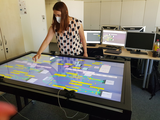 Eine Frau bedient einen großen Touchscreen in einem Büro.