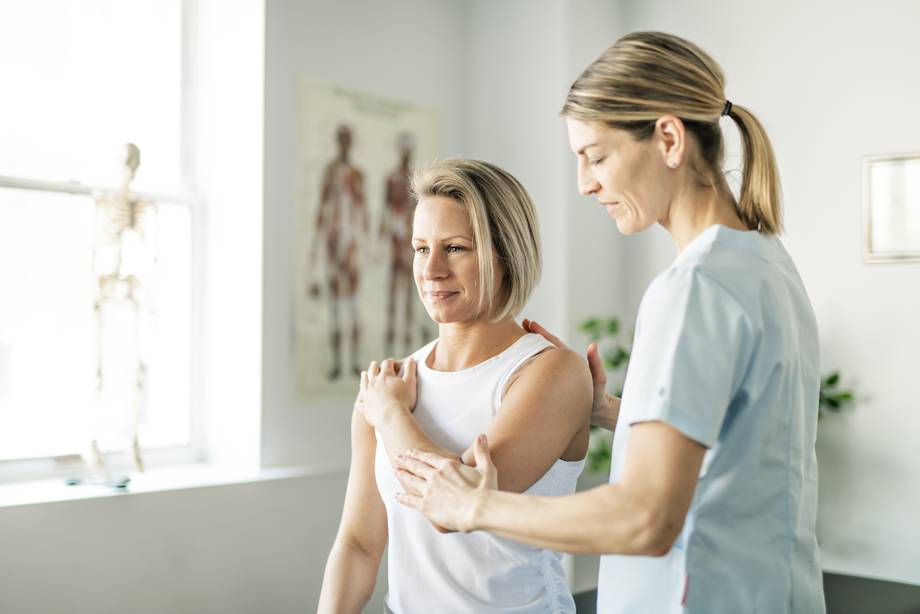 Physiotherapie Behandlung Physiotherapeutin behandelt Patientin an der Schulter