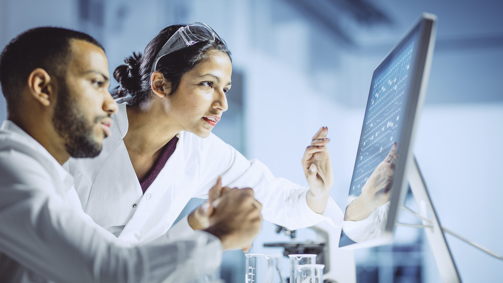 Zwei Medizintechniker schauen gemeinsam auf einen Bildschirm