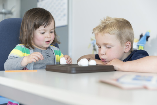 Zwei Kinder sitzen an einem Tisch und spielen mit Tablet-Computern.
