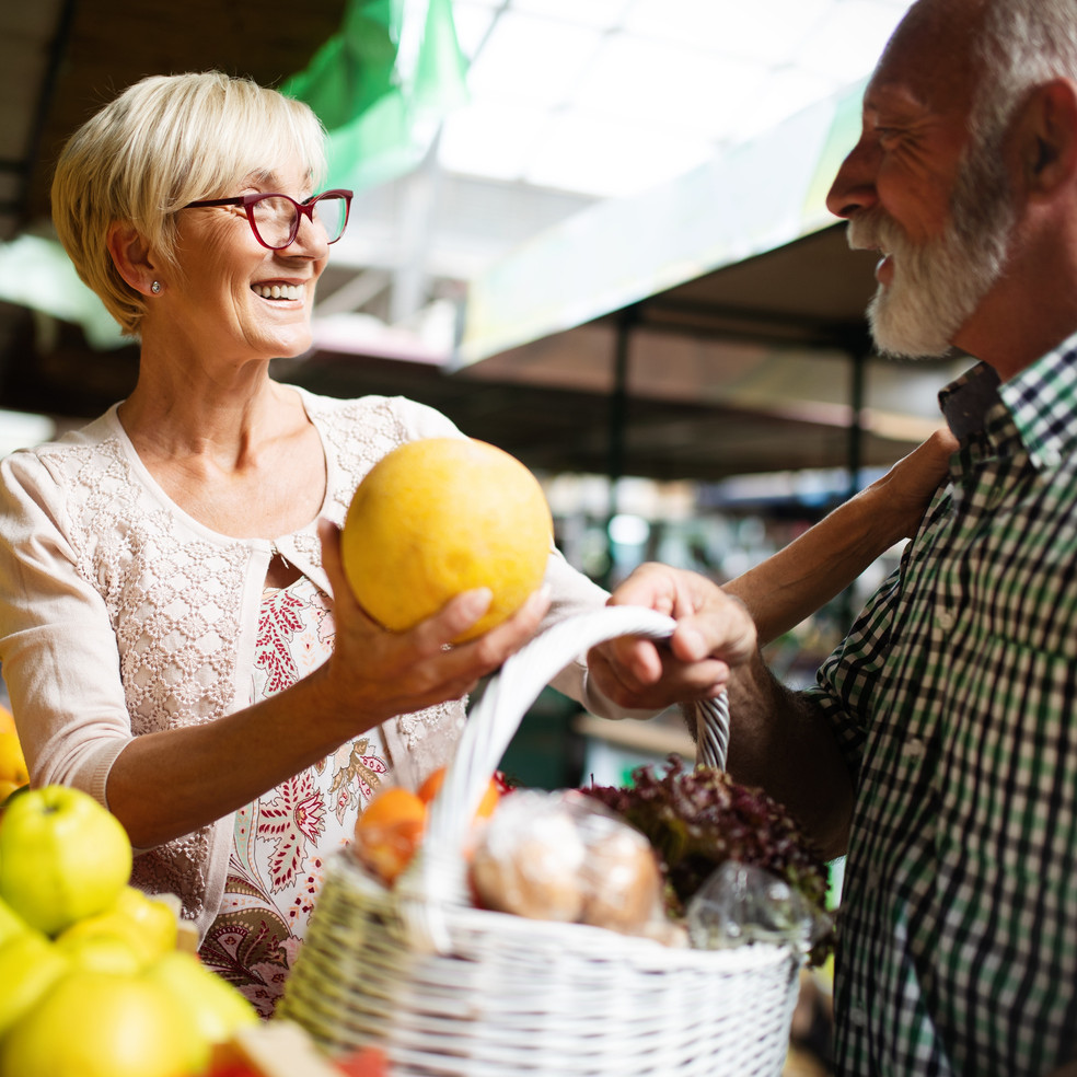 Zwei ältere Menschen kauen Früchte auf dem Markt