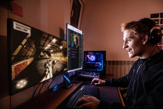 Junger Mann spielt Computerspiel und freut sich